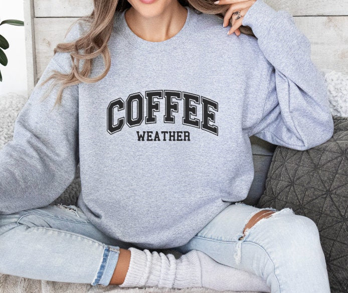 a woman sitting on a couch wearing a coffee sweatshirt