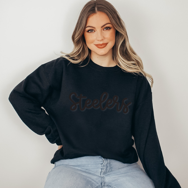 a woman wearing a black sweatshirt with the word steele on it