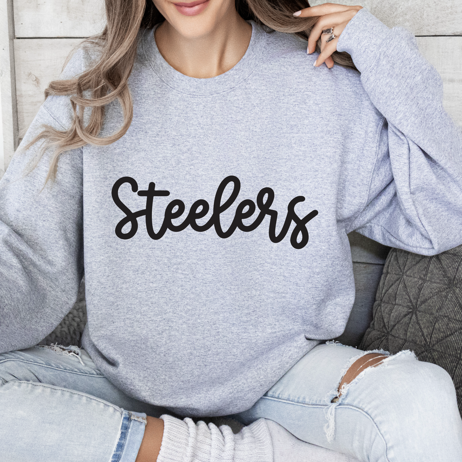 a woman sitting on a couch wearing a sweatshirt with the word steeles on it