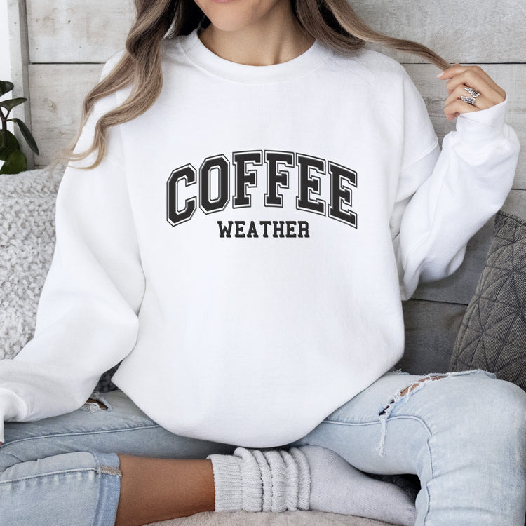 a woman sitting on a couch wearing a coffee sweatshirt