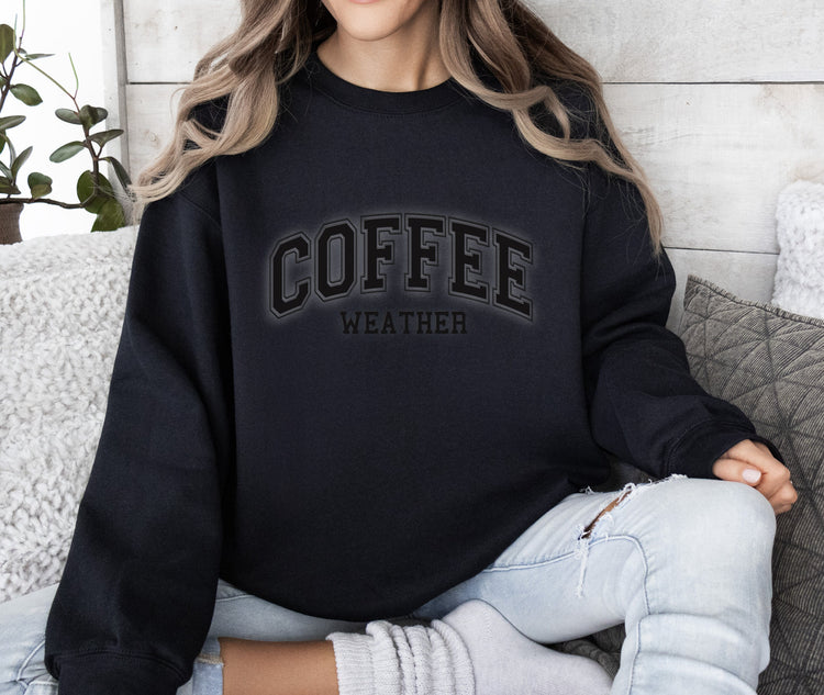 a woman sitting on a couch wearing a coffee sweatshirt